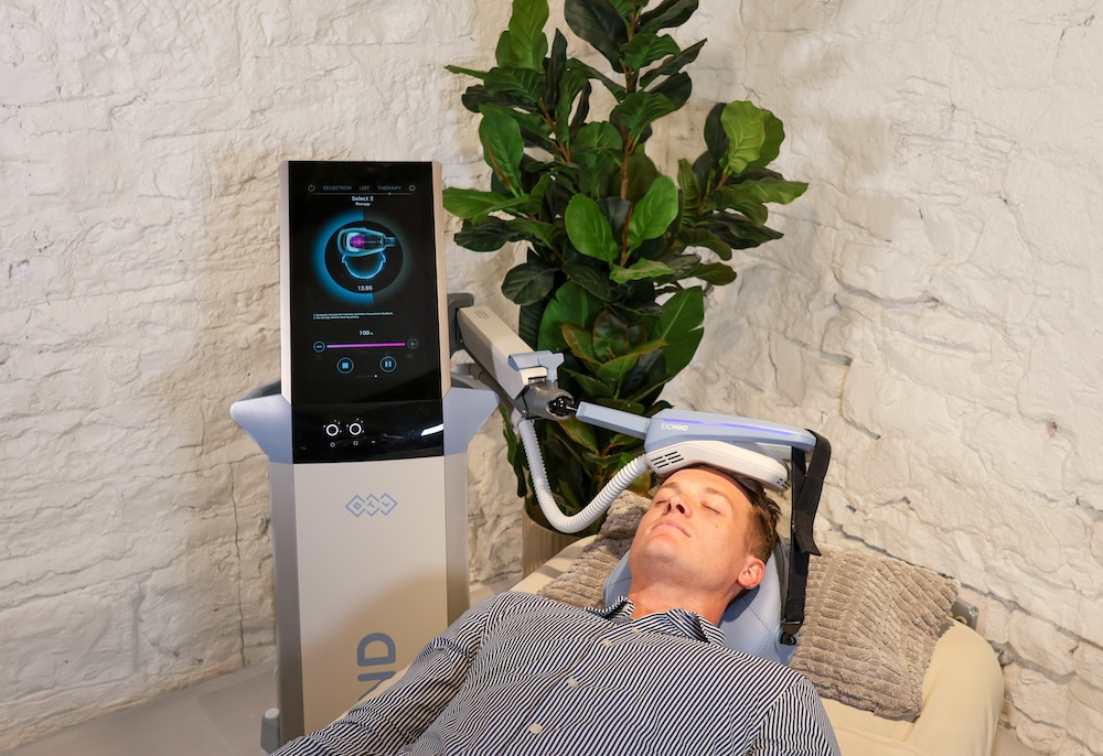 Patient lying on his back in the treatment room for a med spa. There is an applicator placed on his head that reduces anxiety. This is a PTSD treatment in River North, Chicago.