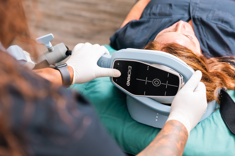 Female patient lying on her back while a provider places the ExoMind applicator on her head as part of a series of OCD treatments in River North, Chicago.