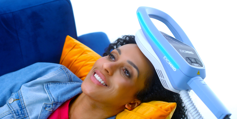 A woman lies down with an Exomind coil placed over her head as one of our OCD treatments in River North Chicago.