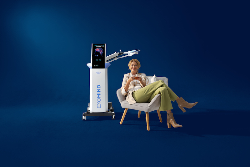 A woman sits down with an Exomind coil positioned over her head as a PTSD treatment in River North Chicago.